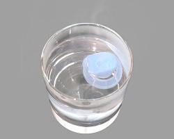 ぬるま湯を入れたコップでボタンを漬け置きしているイメージ写真